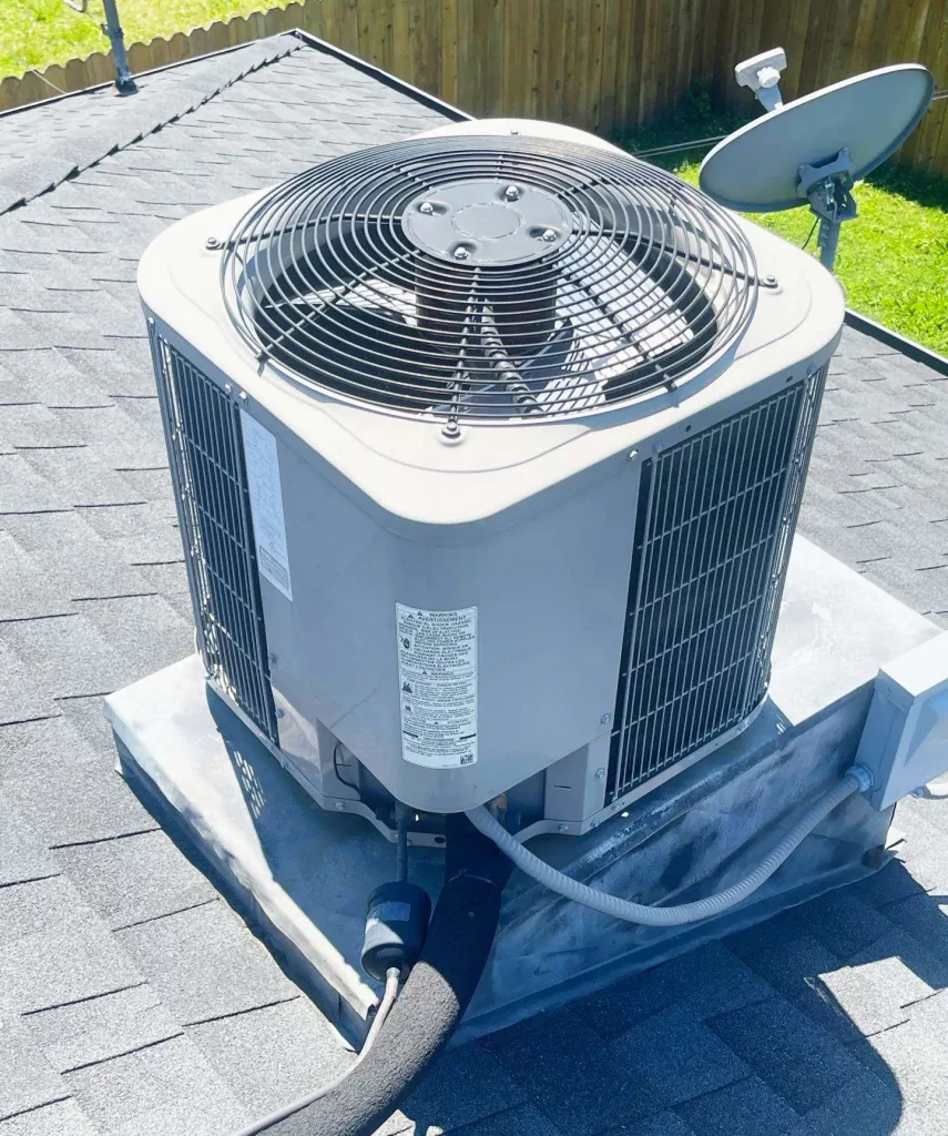 Top 4 Reasons to Choose Spring AC Installation 2 A modern AC condenser unit is installed on a shingled roof, perfect for spring setup. Important product labels are visible on its side.