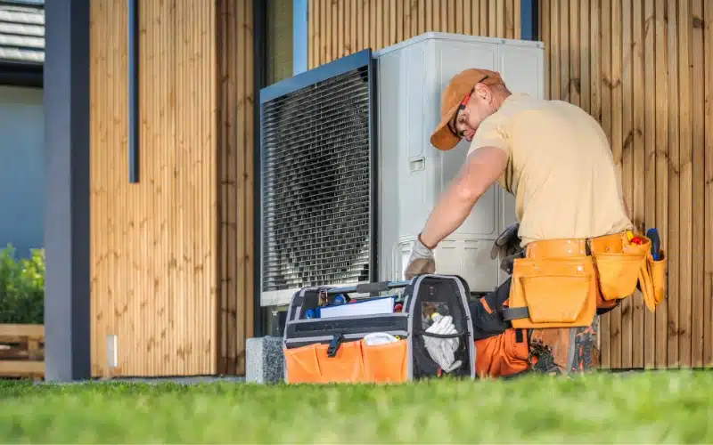 The Benefits of Regular HVAC Maintenance: 1 A skilled HVAC technician inspects an outdoor unit beside a modern home, with tools at the ready.