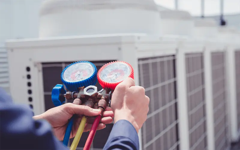 AC Compressor Guide: Common Problems and Solutions 2 A technician uses a manifold gauge set, checking the pressure of an AC system.