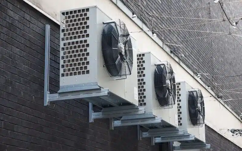 Trusted HVAC Contractor in Sacramento: Prime Genius 2 Four outdoor HVAC condenser units are professionally mounted on a dark brick wall.